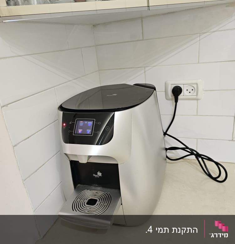 מכונת קפה על משטח במטבח עם כוסות בארון מעל